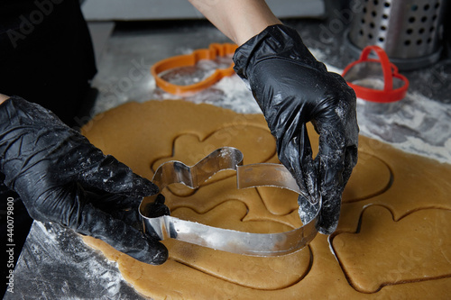 cook with gloved hands makes cookies using a dough mold