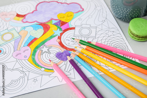 Coloring picture and pencils on table, closeup