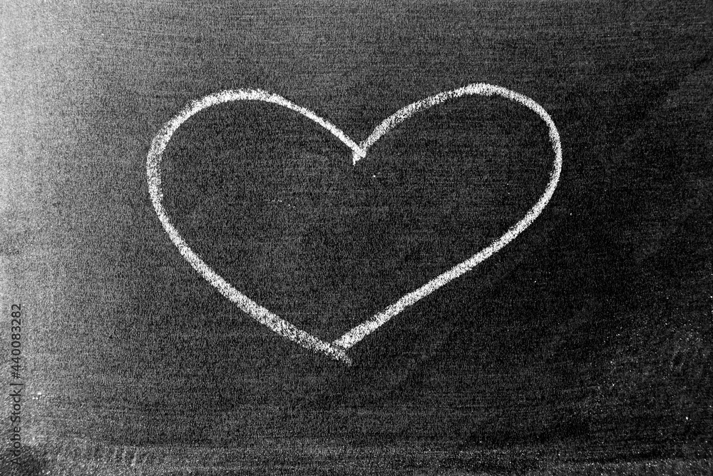 White color chalk hand drawing in heart shape on blackboard or chalkboard background White color chalk hand drawing in heart shape on blackboard or chalkboard background