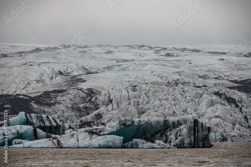 The Solheimajokull Glacier in Iceland showing icebergs and calved ice in the lagoon as ice calves and melts together with the erosion caused by the receding glacier photo