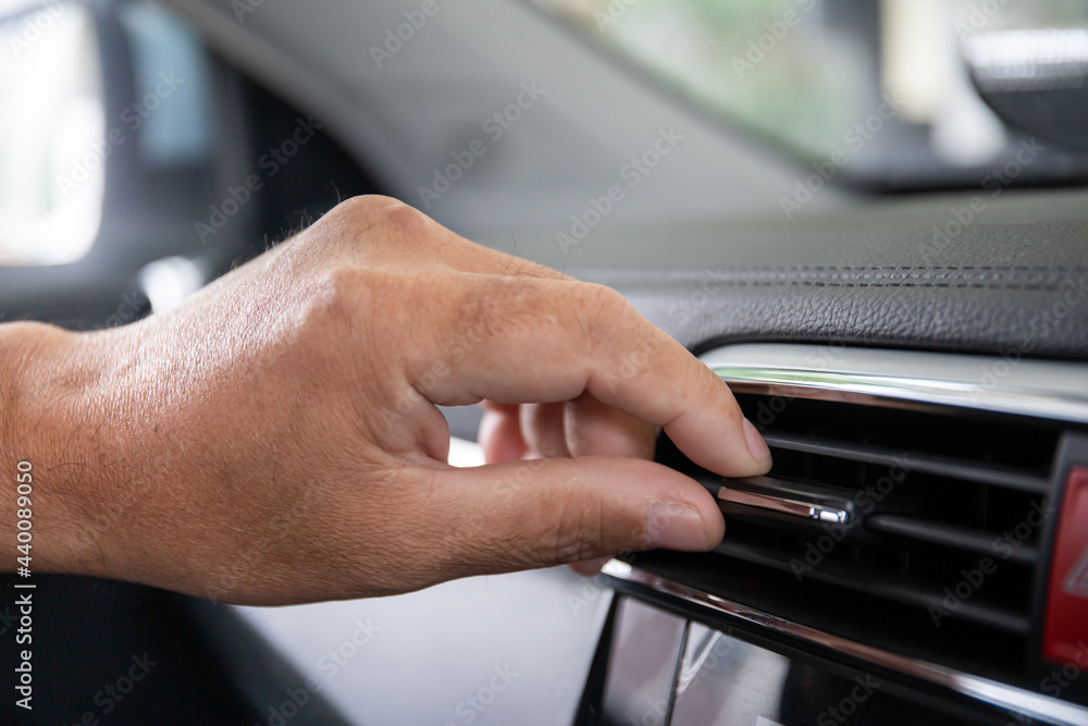 Unrecognizable man adjusting the vehicle air conditioner grille for better air flow.