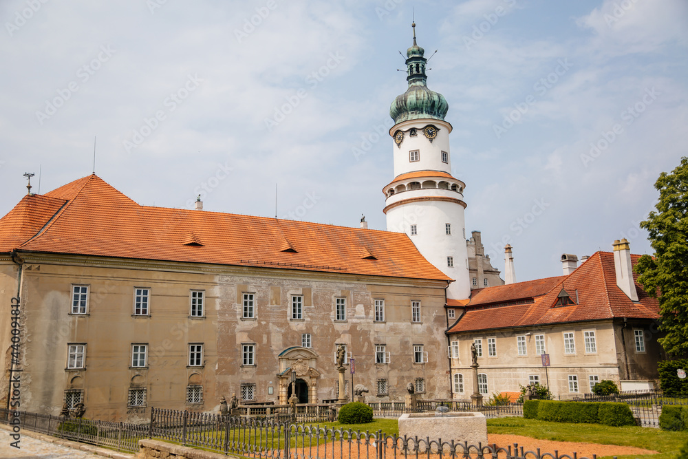Fototapeta premium Baroque romantic castle Nove mesto nad Metuji, renaissance chateau with round white clock tower, red tile roof, arched portal entrance, summer sunny day Eastern Bohemia, Czech Republic