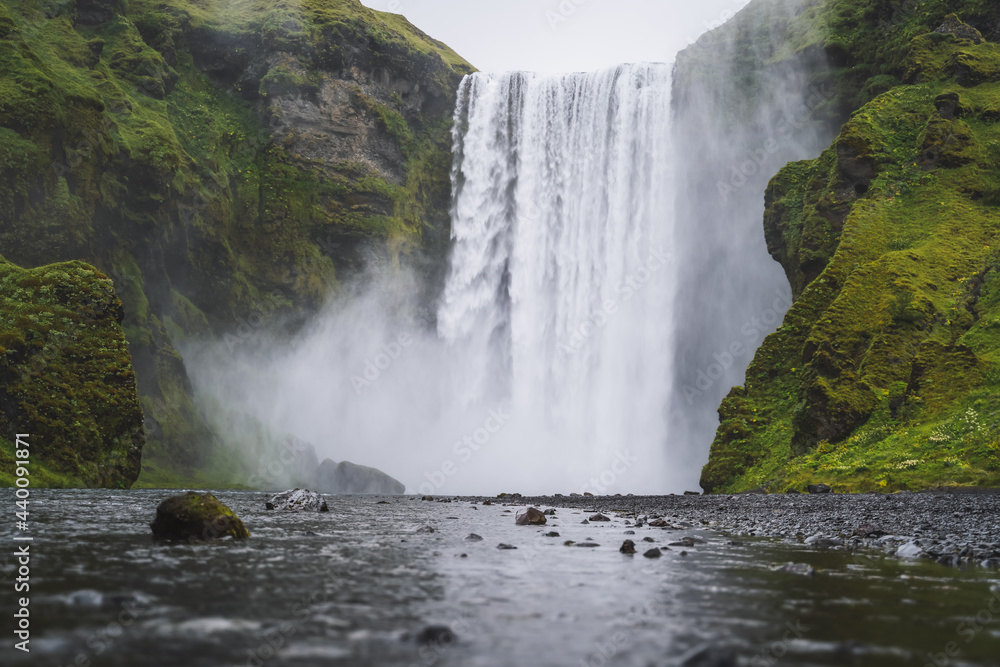 Fototapeta premium Beautiful Skogafoss waterfall. The most popular destination in Iceland. Water falling down a beautiful valley building reflection in river below