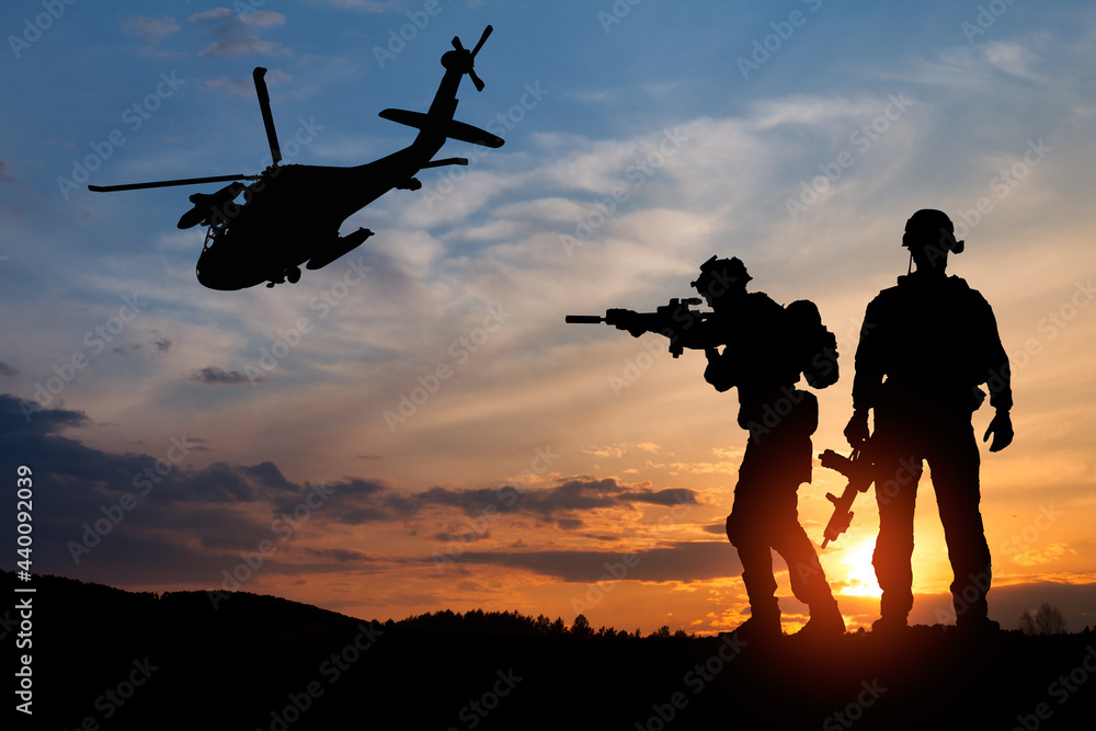 Silhouette of a soldiers and helicopter on the background of sunset. Concept - protection, patriotism, honor.