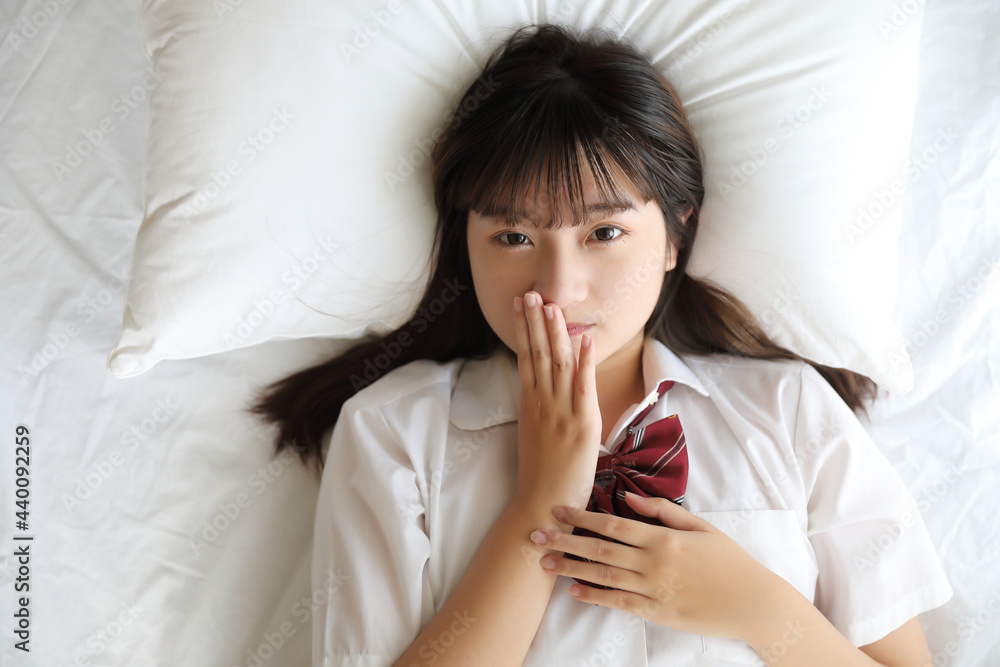 Portrait japanese school girl uniform sleep and look at camera in white tone bed room Portrait japanese school girl uniform sleep and look at camera in white tone bed room