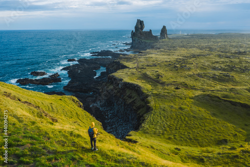 Man hiker in yellow jacket stand on the peak of the rock in outdoor park in Iceland. Londrangar photo