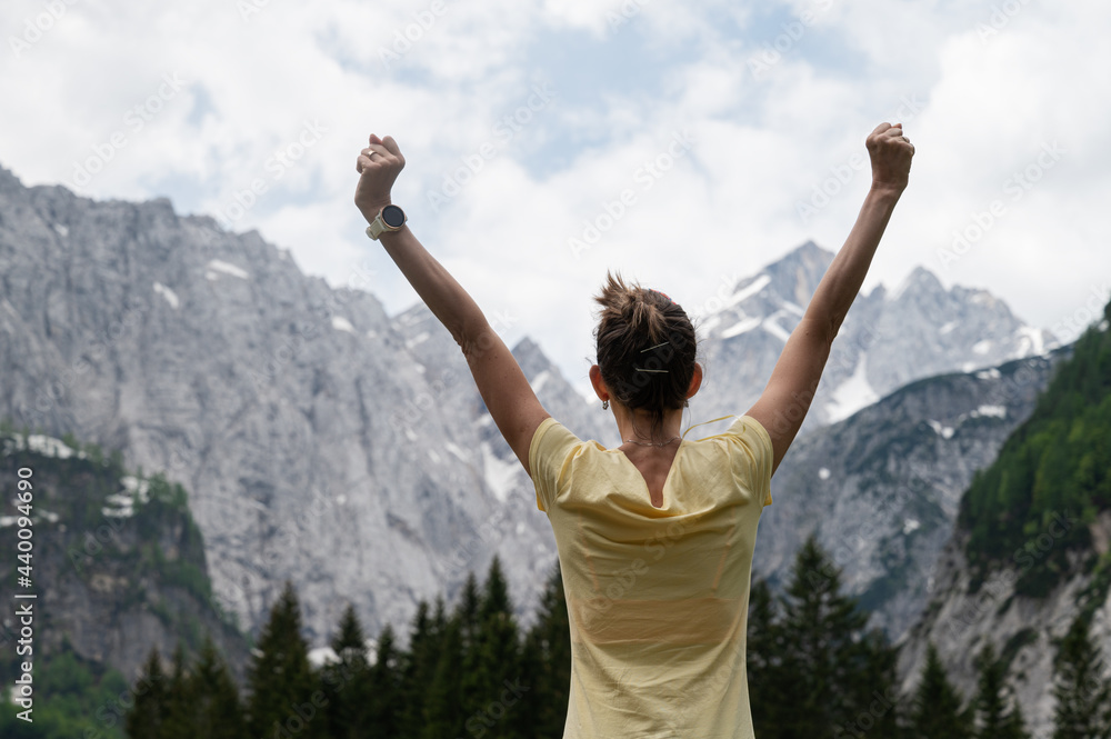 Young woman standing under beautiful rocky mountains Young woman standing under beautiful rocky mountains