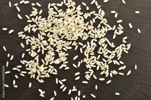 White uncooked rice, close-up, on a slate board, top view.