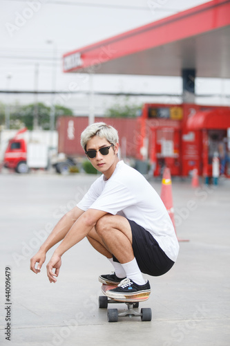 asian young man wear sunglasses playing skateboard on street city.  skateboarding outdoor sports. © eakgrungenerd
