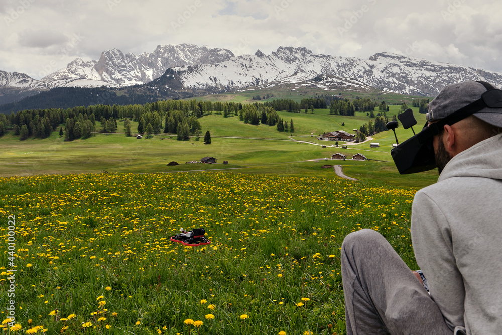 Man driving an FPV drone in an idyllic landscape like the Alpe di Siusi in the Italian Dolomites