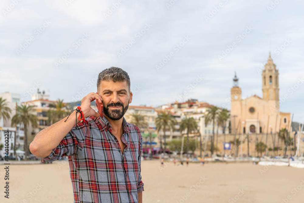 Portrait of beautiful caucasian man on the beach talking on mobile phone