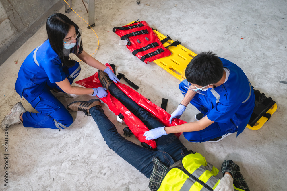Fototapeta premium Emergency medical teams are helping a construction worker with a broken leg accident at a construction site. Safety team help employee accident.