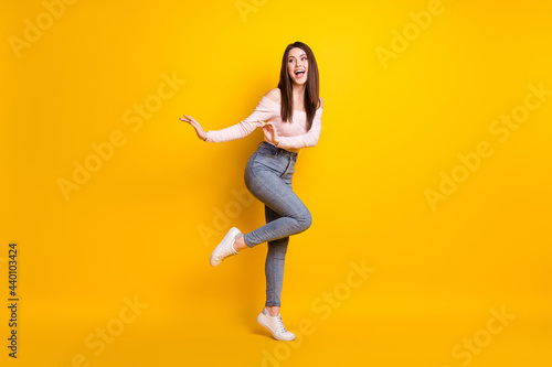 Full size photo of young funky funny smiling woman look copyspace dreaming dancing isolated on yellow color background