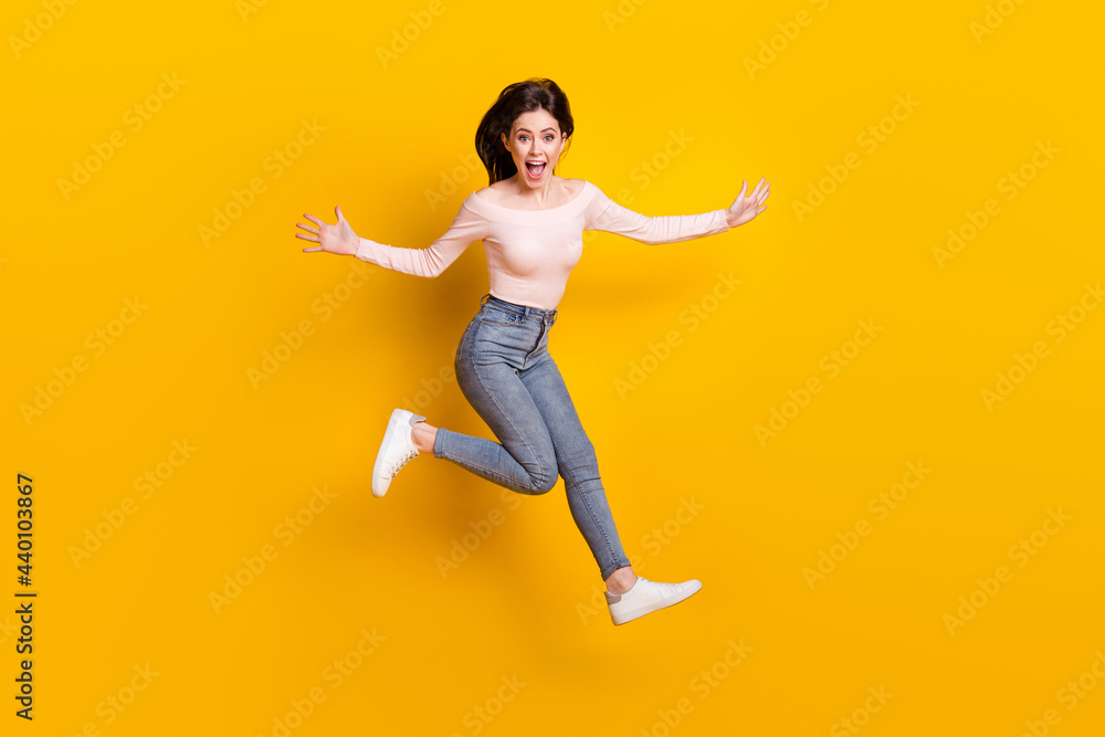Full size photo of young happy excited funky girl jumping running in iar screaming isolated on yellow color background