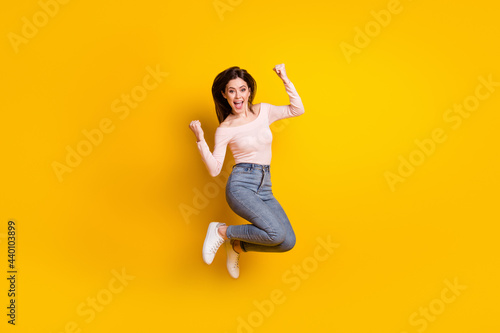 Full size photo of young happy excited cheerful woman jumping in victory success isolated on yellow color background