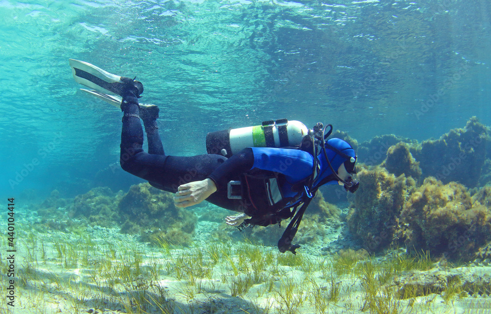 A scuba diver dives from the surface to the bottom. The diver begins his dive underwater. Diver shows balance under water A scuba diver dives from the surface to the bottom. The diver begins his dive underwater. Diver shows balance under water