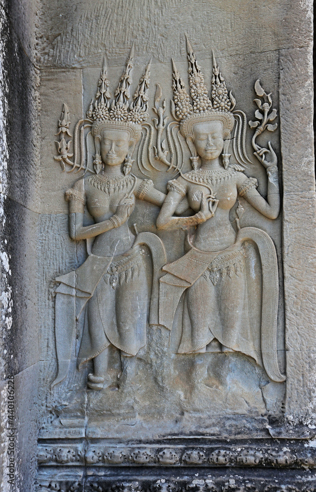 Stone bas-relief with human figures in Angkor Wat temple, Siem Reap, Cambodia. Female figures stone carving on ancient temple wall panel. Cambodian traditional art and craft. Tourist sightseeing photo