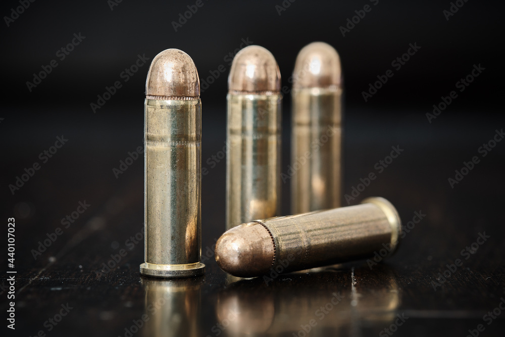 Brass handgun ammunition against a wooden backdrop Brass handgun ammunition against a wooden backdrop