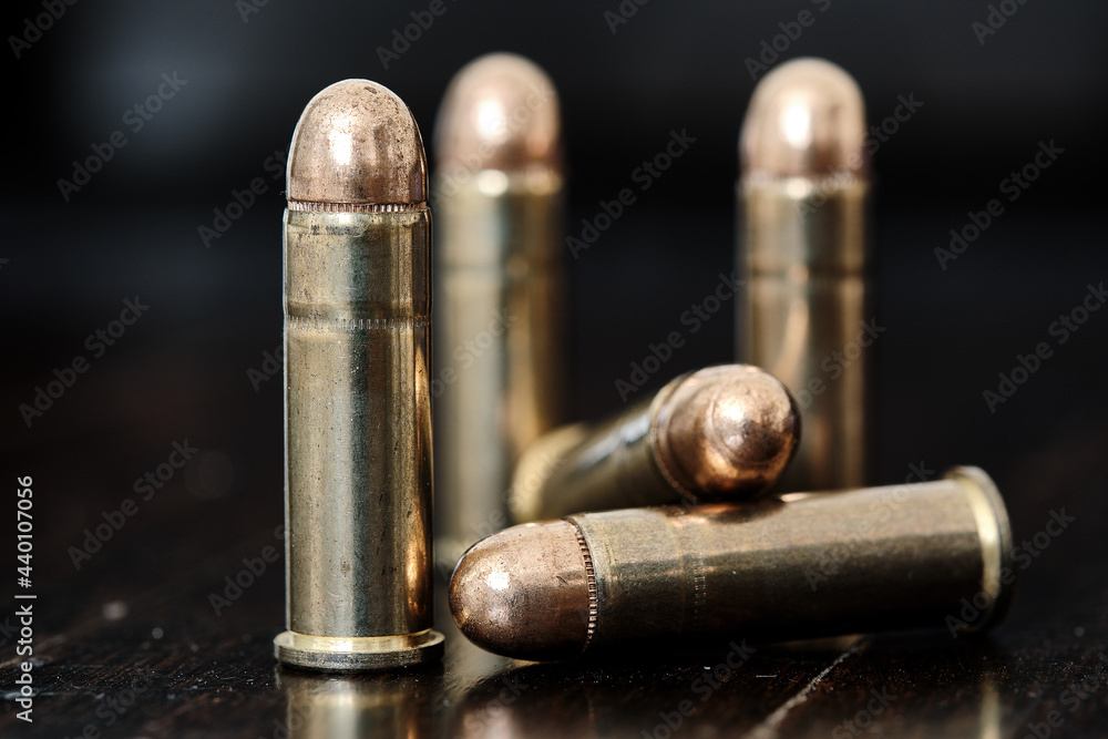 Brass handgun ammunition against a wooden backdrop Brass handgun ammunition against a wooden backdrop