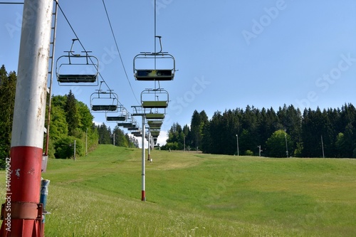 View on chairs of ski lift in abandoned ski resort , Jasenska dolina, located in the Turiec region, Slovakia, during summer. Hill is covered with green grass and surrounded with coniferous forest. photo