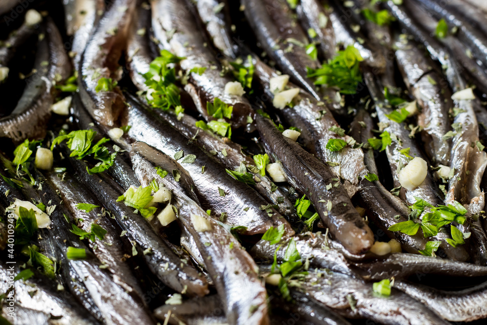 Close-up of fresh anchovies to be cooked in a pan with garlic and parsley. Close-up of fresh anchovies to be cooked in a pan with garlic and parsley.