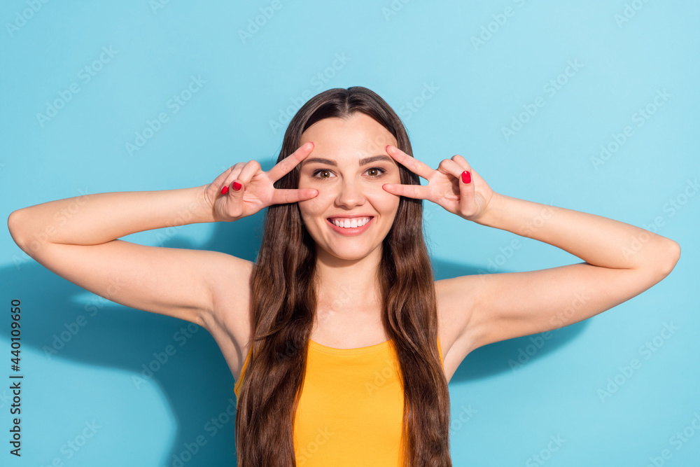 Photo portrait girl showing v-sign gesture peace sign cheerful girlish isolated pastel blue color background Photo portrait girl showing v-sign gesture peace sign cheerful girlish isolated pastel blue color background