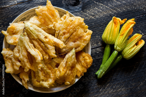 Fried zucchini flowers in batter on wooden background