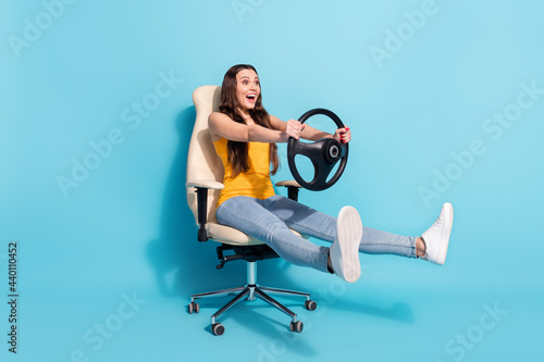 Full length body size photo girl keeping steering wheel sitting in office chair isolated pastel blue color background photo