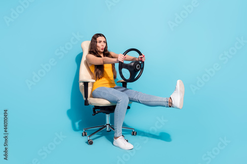 Full length body size photo girl keeping steering wheel sitting in office chair imagine driving car isolated pastel blue color background