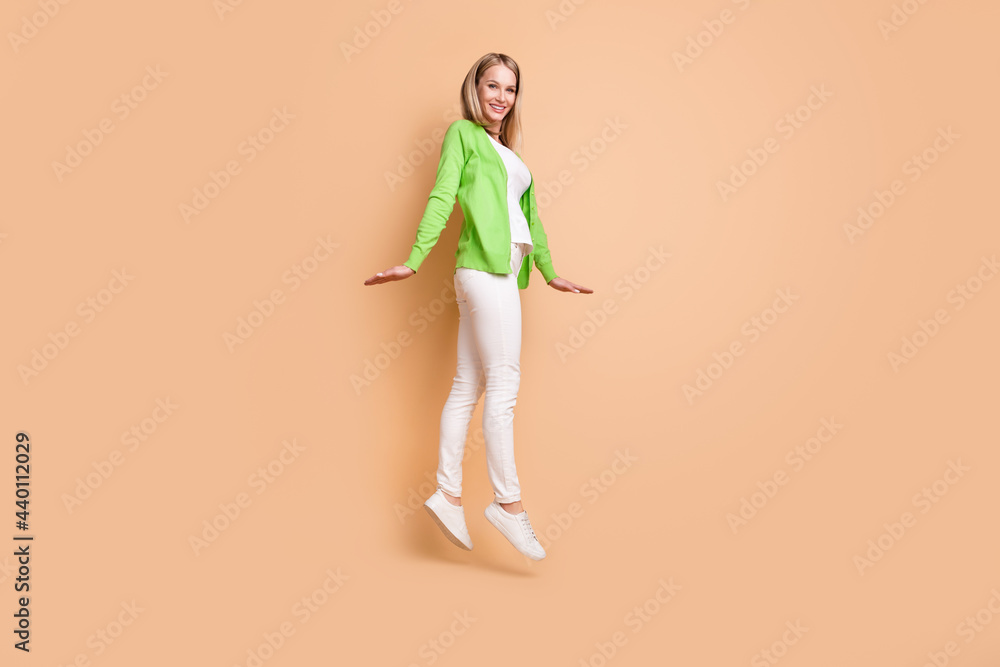 Full length body size photo pretty woman smiling jumping up isolated pastel beige color background copyspace Full length body size photo pretty woman smiling jumping up isolated pastel beige color background copyspace
