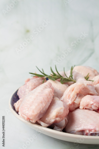 Raw chicken wings with herbs, over a blue plate, green background