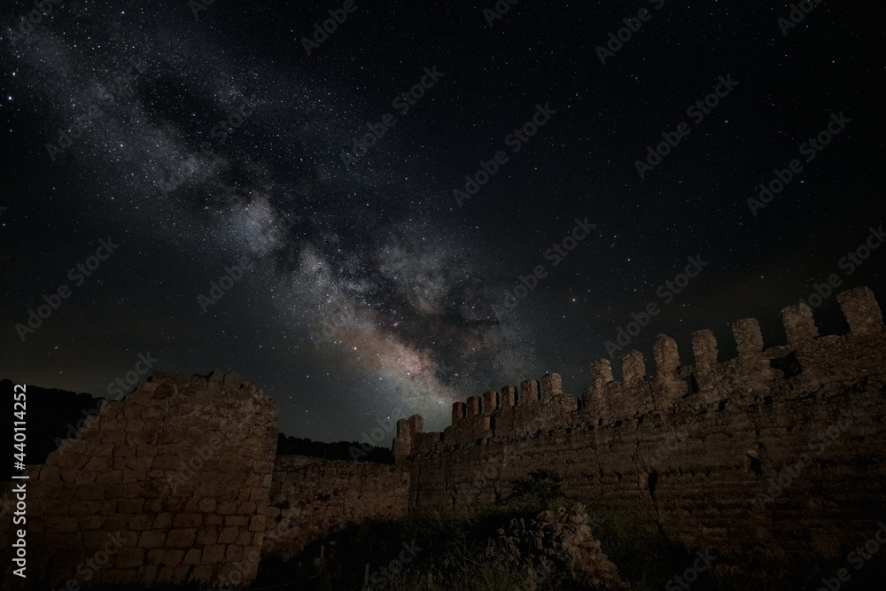 Old castle ruins surrounded by a starry sky view with the Milky Way in the middle