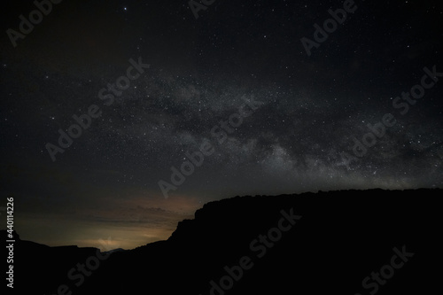 Starry sky view with the Milky Way in the middle. Moutains silhouettes over the dark and starry sky © Julian