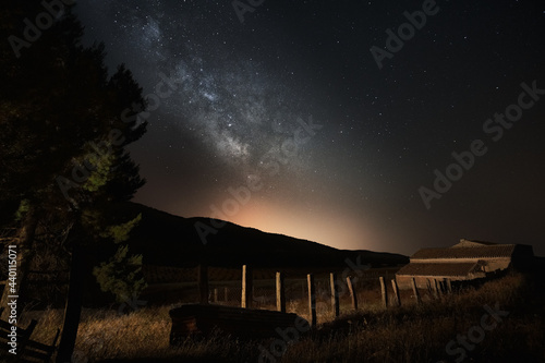 Old cottage surrounded by a starry sky view with the Milky Way in the middle