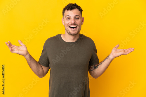 Young caucasian handsome man isolated on yellow background with shocked facial expression