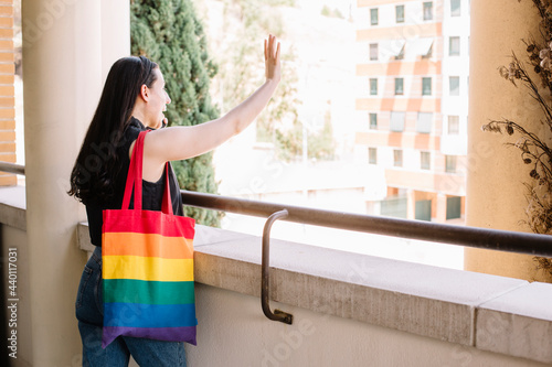Young woman with rainbow bag greeting female friends on street