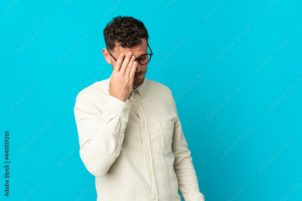 Young caucasian handsome man isolated on blue background with headache