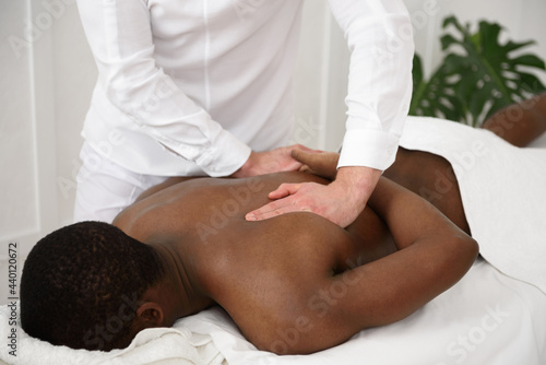 African american man having back massage in spa, white background. Copy space, closeup