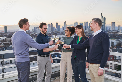 Male and female colleagues toasting drinks after work on terrace photo