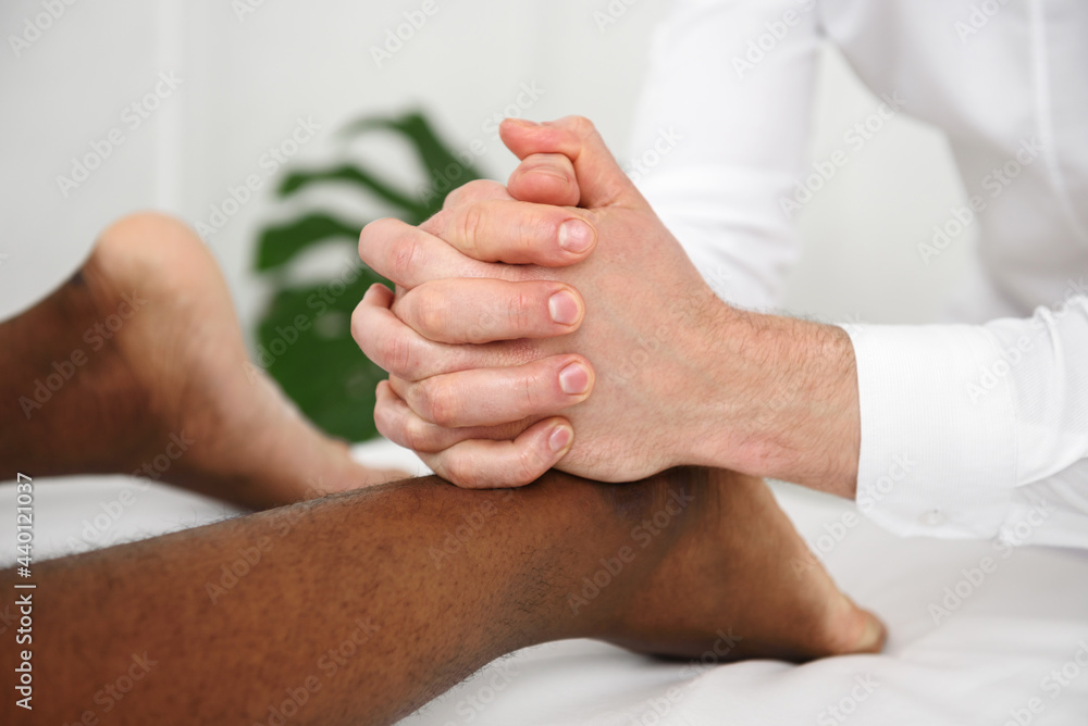 Fototapeta premium African american man having foot massage in spa, white background. Copy space, closeup