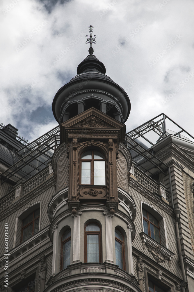 A beautiful old house with a tower and large windows. Gray cloudy sky. Ancient architecture. A beautiful old house with a tower and large windows. Gray cloudy sky. Ancient architecture.
