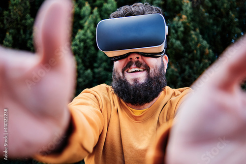 Smiling man wearing virtual reality simulator in garden photo