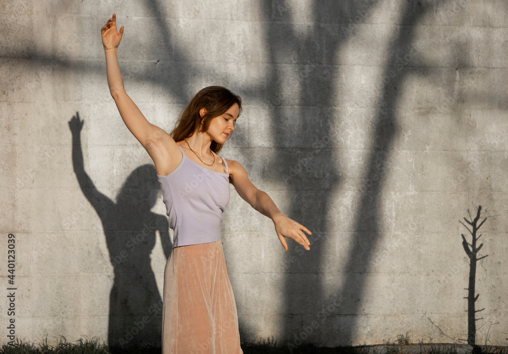 Woman with arms raised dancing against wall Woman with arms raised dancing against wall