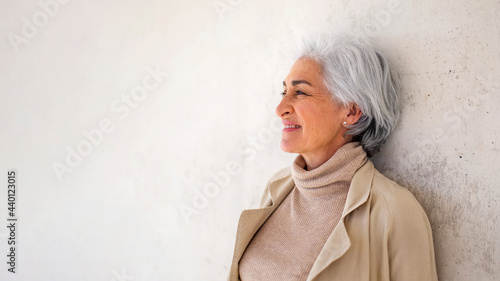 Smiling woman with short hair day dreaming in front of white wall photo