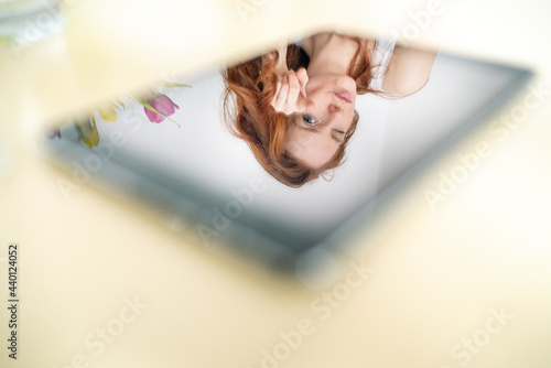 Reflection of woman on digital tablet over table at home