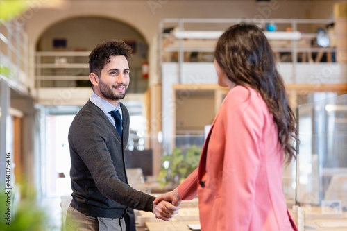 Young businessman shaking hands with female entrepreneur in coworking office photo