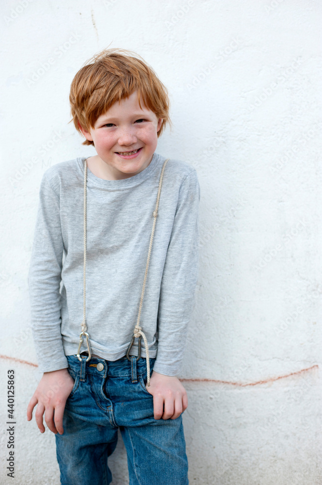 Curious boy with hands in pockets standing in front of wall outdoors Curious boy with hands in pockets standing in front of wall outdoors