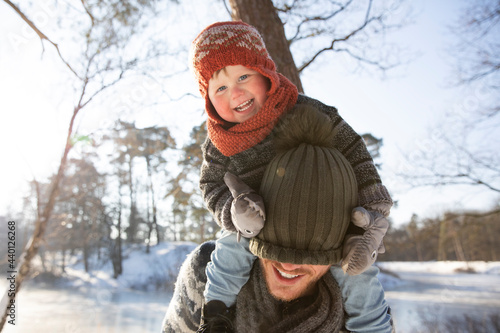 Smiling son pulling knit hat over father's face during winter photo