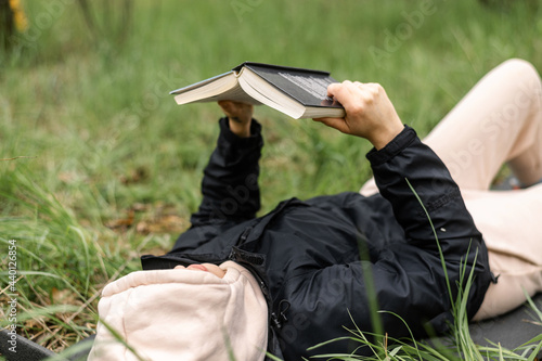 A woman lies on the grass and reads a book. Camping, relaxation.