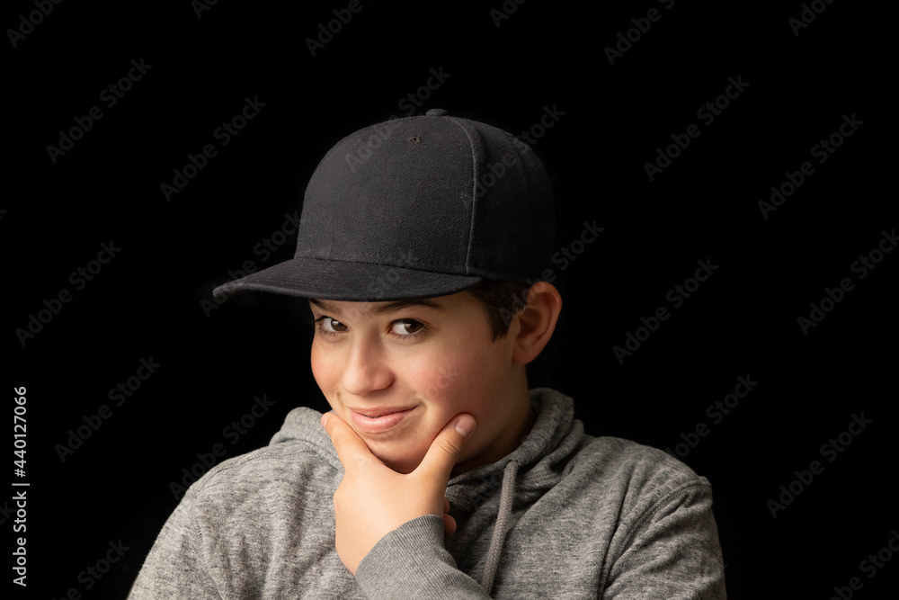 Smiling boy with hand on chin in front of black background Smiling boy with hand on chin in front of black background